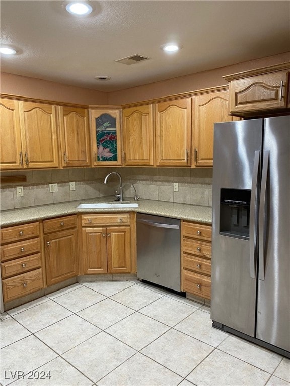 kitchen featuring decorative backsplash, sink, light tile patterned floors, and stainless steel appliances