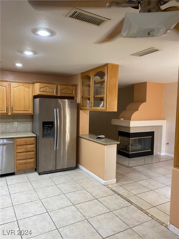 kitchen featuring tasteful backsplash, light tile patterned flooring, a textured ceiling, and appliances with stainless steel finishes