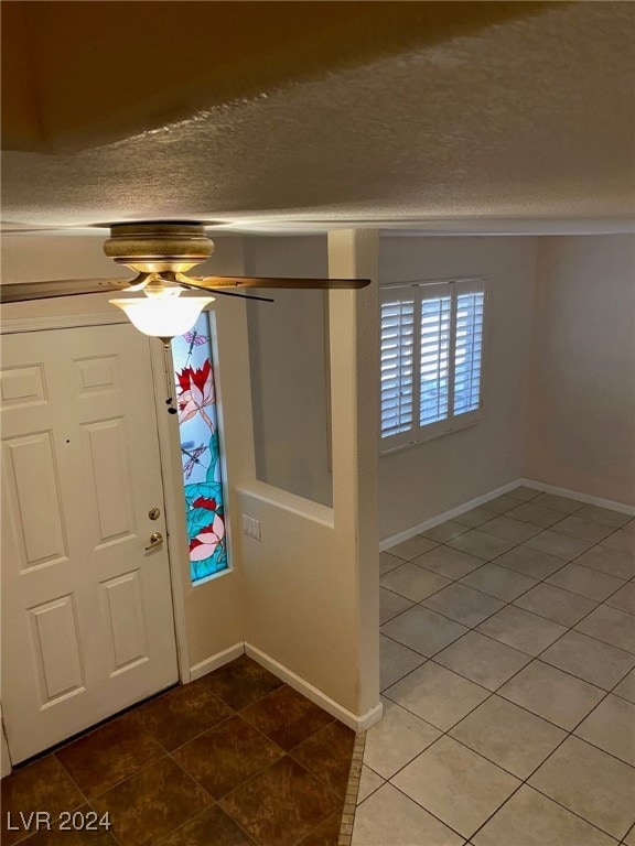 entryway featuring ceiling fan, tile patterned flooring, and a textured ceiling