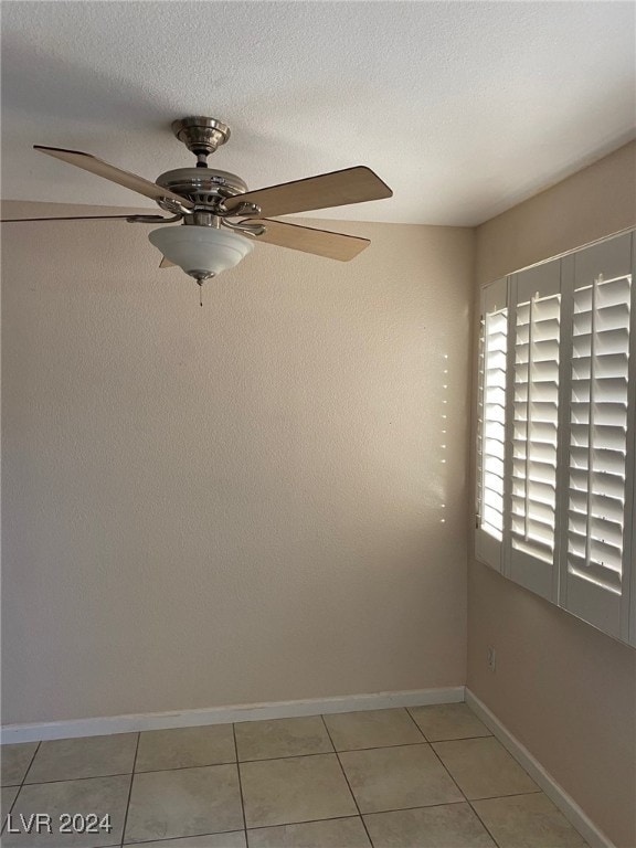 tiled empty room featuring ceiling fan and a textured ceiling