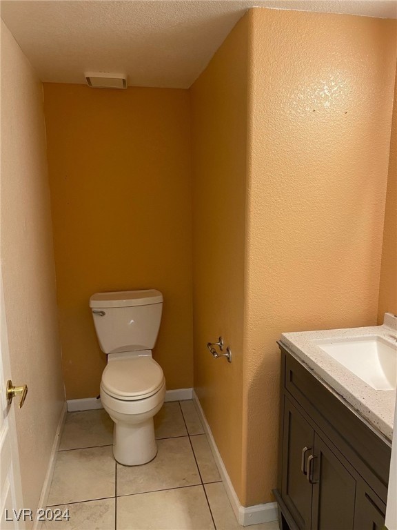 bathroom featuring tile patterned flooring, vanity, a textured ceiling, and toilet