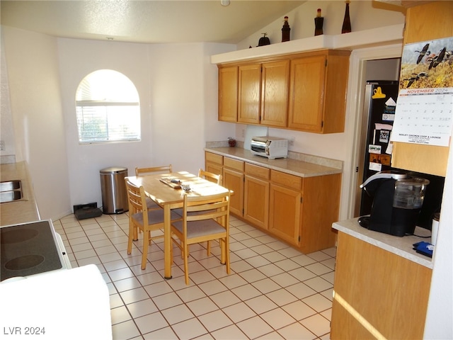 kitchen featuring light tile patterned floors, stainless steel refrigerator, and vaulted ceiling