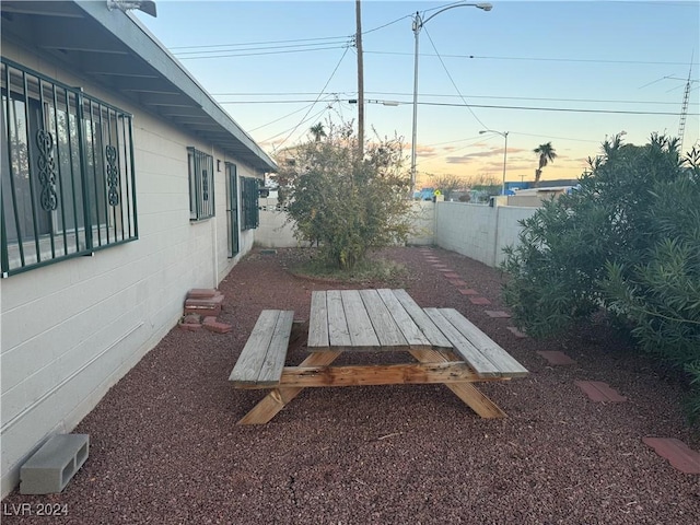 yard at dusk with outdoor dining area and a fenced backyard