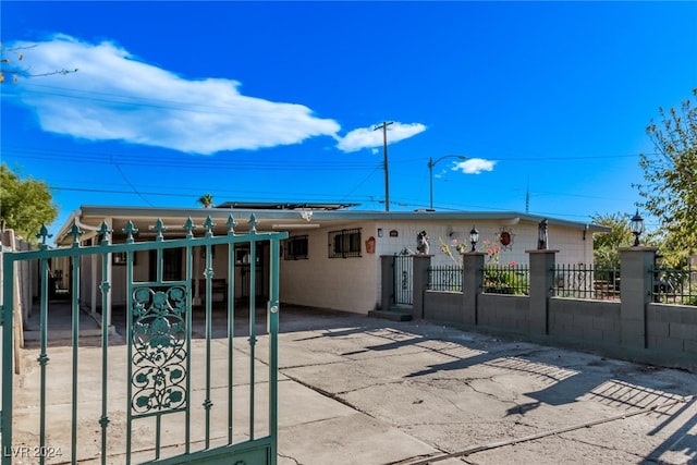 view of front of property with a fenced front yard, an attached carport, concrete block siding, and driveway