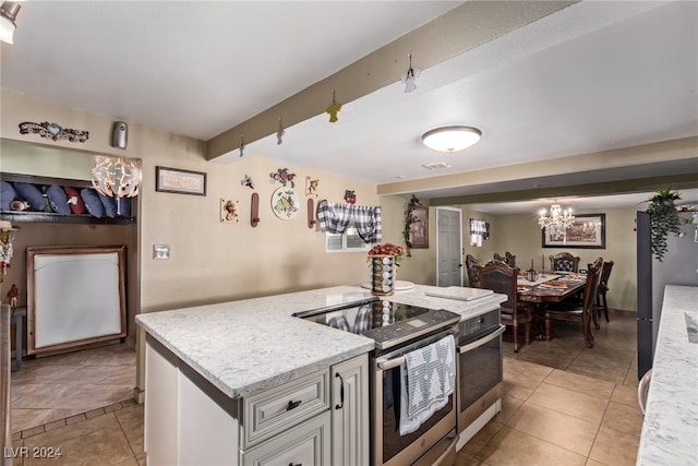 kitchen featuring light tile patterned floors, beam ceiling, appliances with stainless steel finishes, and light stone countertops