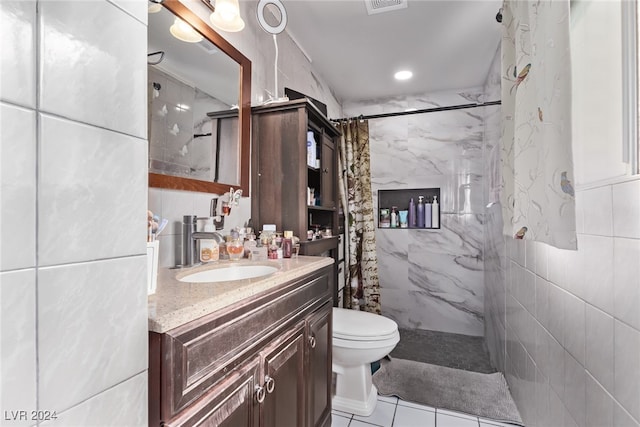 full bath featuring a marble finish shower, tile walls, and vanity