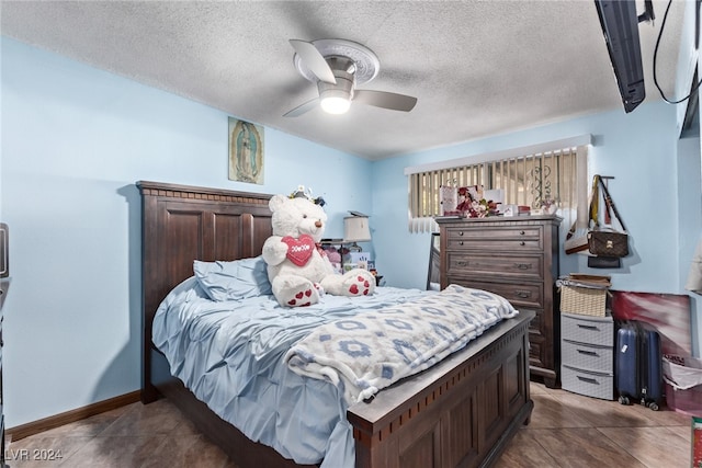 bedroom featuring baseboards, a textured ceiling, dark tile patterned floors, and a ceiling fan