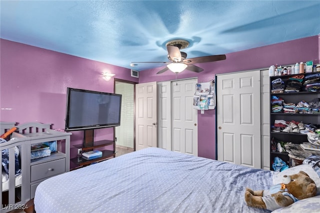 bedroom with a textured ceiling, two closets, and ceiling fan