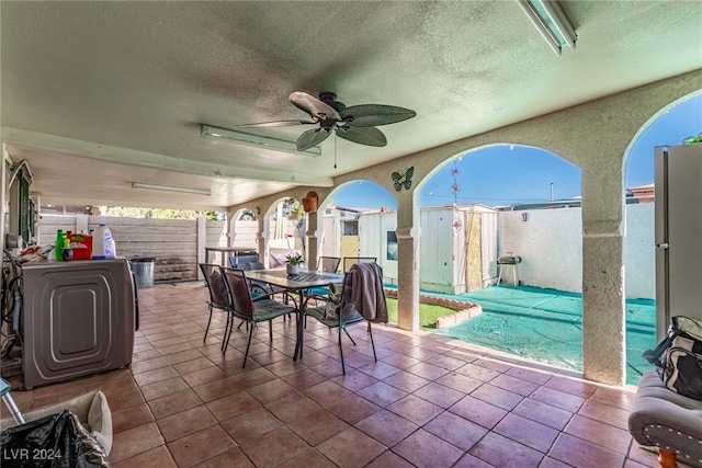 view of patio with a ceiling fan, a fenced backyard, grilling area, outdoor dining area, and washer / dryer