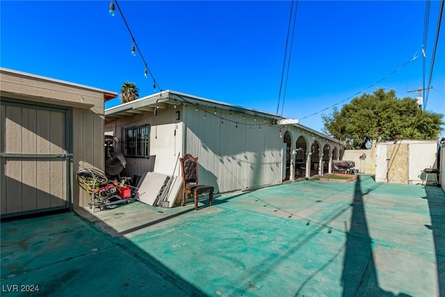 exterior space with an outbuilding, fence, a shed, and a patio