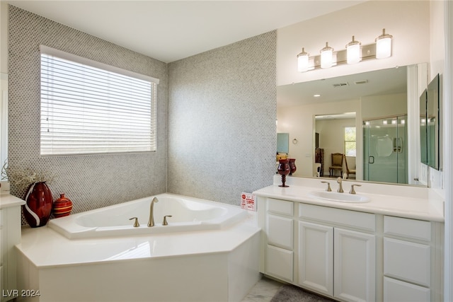 bathroom featuring separate shower and tub, vanity, and a healthy amount of sunlight