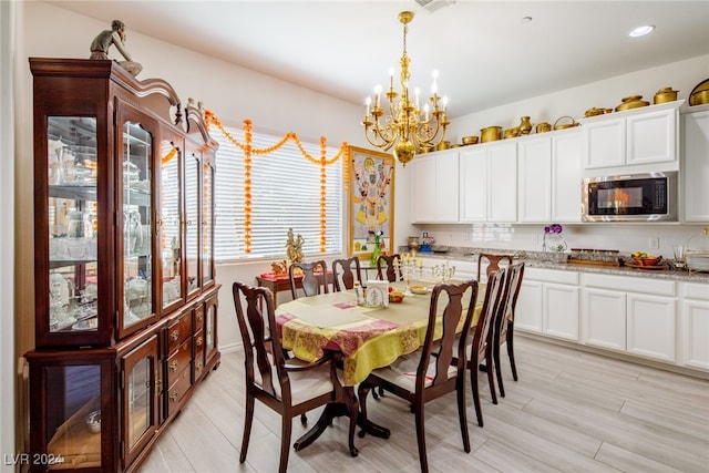 dining room with light wood-type flooring and a chandelier