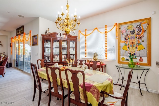 dining area with light wood-type flooring, plenty of natural light, and a notable chandelier