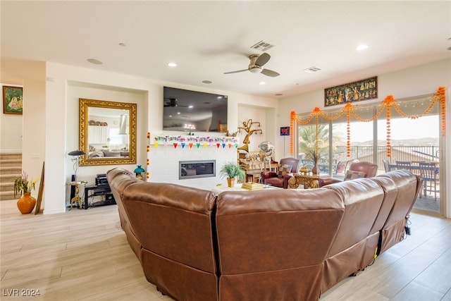 living room featuring ceiling fan, a fireplace, and light hardwood / wood-style floors