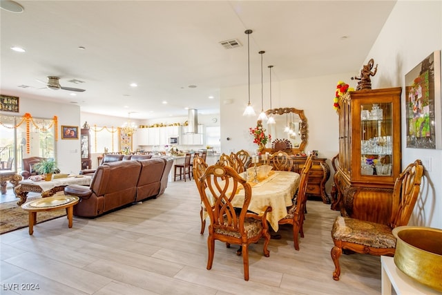 dining space featuring light hardwood / wood-style floors and ceiling fan with notable chandelier