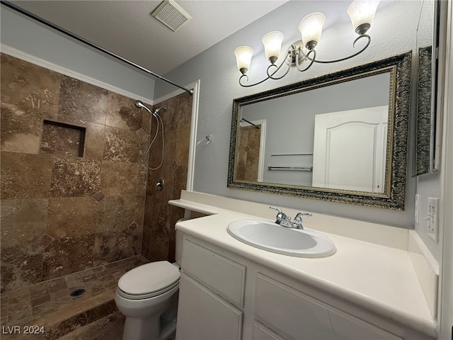 bathroom featuring a tile shower, vanity, a textured ceiling, and toilet