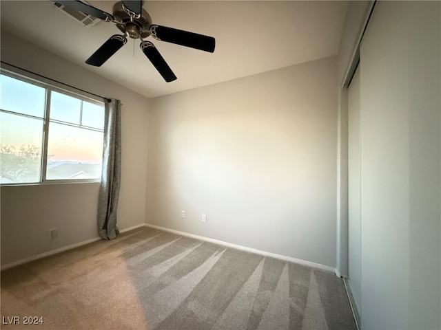 carpeted spare room featuring ceiling fan