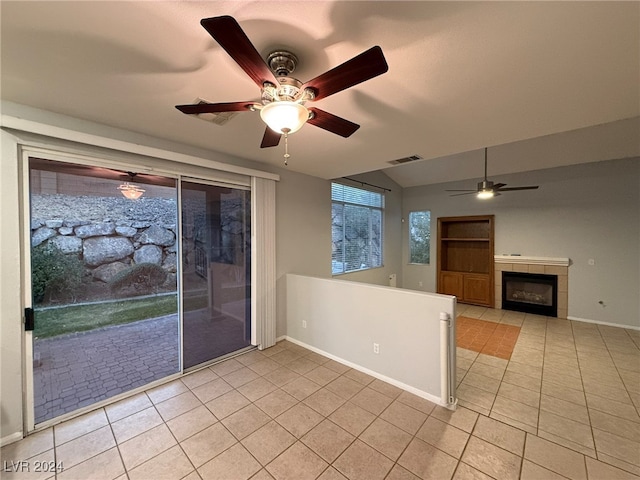 interior space featuring a tiled fireplace, ceiling fan, and light tile patterned floors