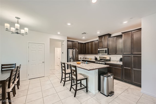 kitchen featuring stainless steel appliances, sink, decorative light fixtures, an inviting chandelier, and an island with sink