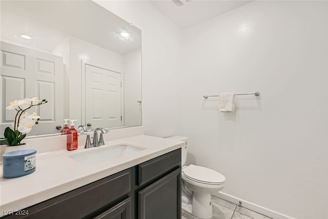 bathroom with toilet, vanity, and tile patterned floors