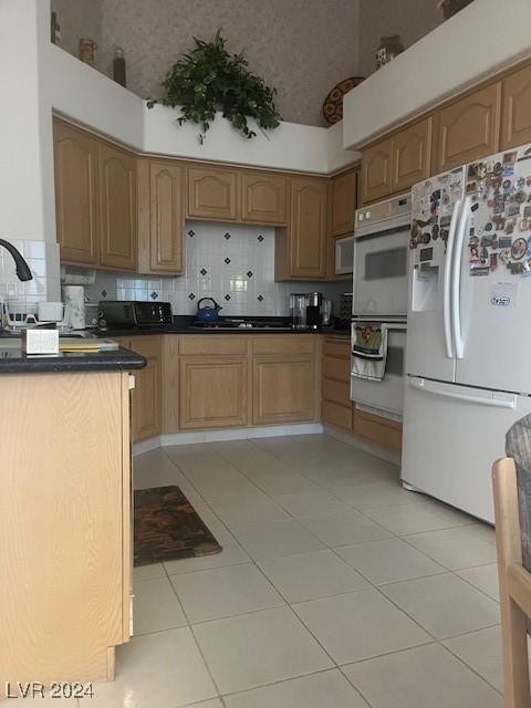 kitchen with light tile patterned floors, white appliances, a high ceiling, and tasteful backsplash