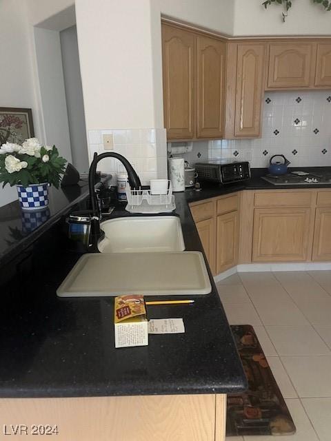 kitchen featuring backsplash, light tile patterned floors, sink, and gas cooktop