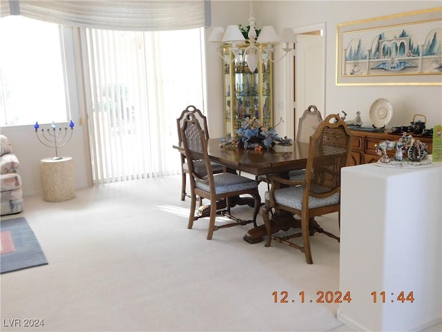 carpeted dining room featuring a notable chandelier