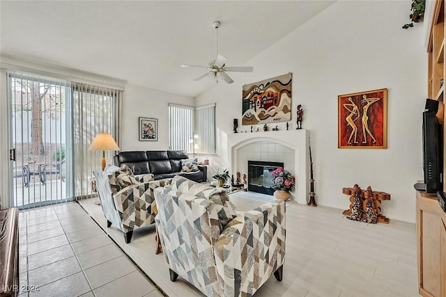 living room featuring vaulted ceiling, ceiling fan, and a tiled fireplace