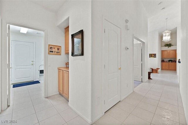 hall with light tile patterned floors and an inviting chandelier