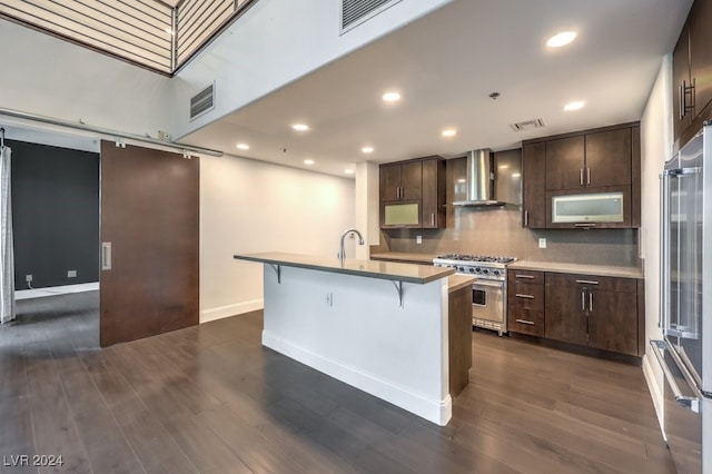 kitchen featuring wall chimney exhaust hood, a kitchen breakfast bar, dark hardwood / wood-style floors, high quality appliances, and a center island with sink