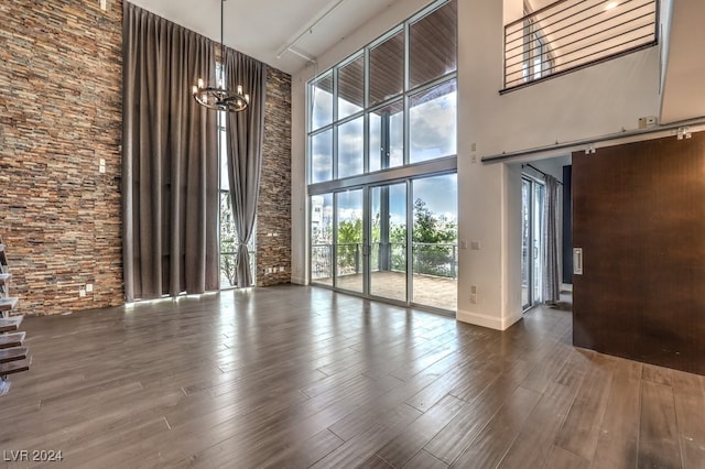 interior space featuring a towering ceiling, a notable chandelier, and hardwood / wood-style flooring