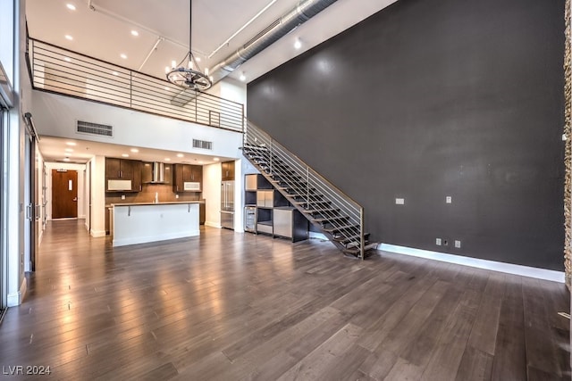 unfurnished living room with a chandelier, a high ceiling, and dark hardwood / wood-style floors