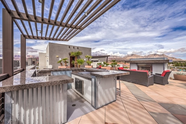 view of patio / terrace with outdoor lounge area, an outdoor kitchen, a pergola, and a wet bar