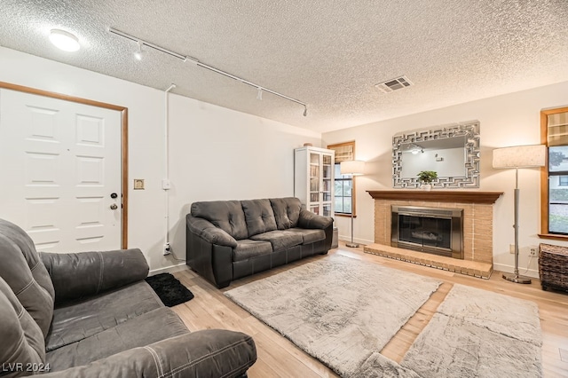 living room featuring track lighting, a textured ceiling, and light hardwood / wood-style flooring