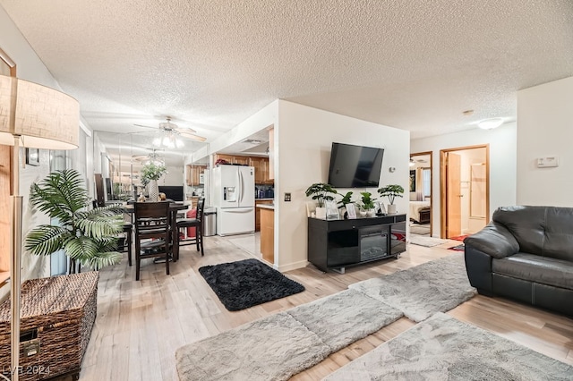 living room with ceiling fan, light hardwood / wood-style flooring, and a textured ceiling