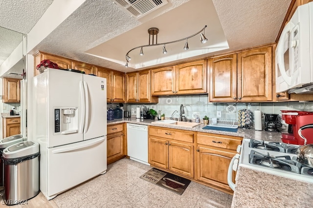 kitchen featuring a textured ceiling, a raised ceiling, white appliances, and sink