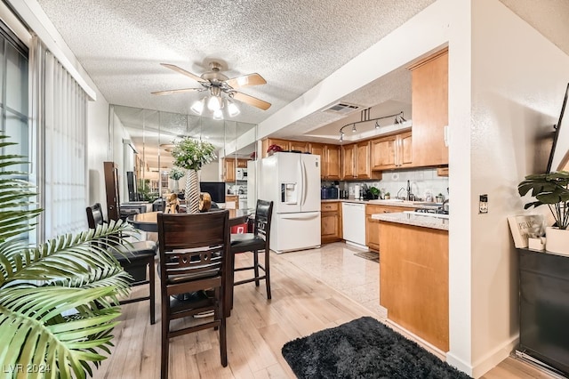 kitchen featuring sink, tasteful backsplash, light hardwood / wood-style flooring, a textured ceiling, and white appliances