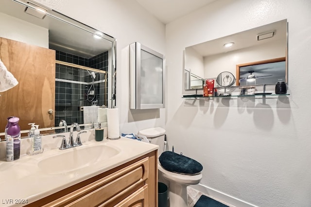 bathroom with vanity, toilet, ceiling fan, and a shower with shower door