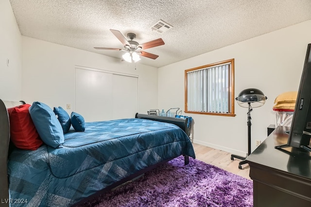 bedroom with a textured ceiling, light wood-type flooring, a closet, and ceiling fan