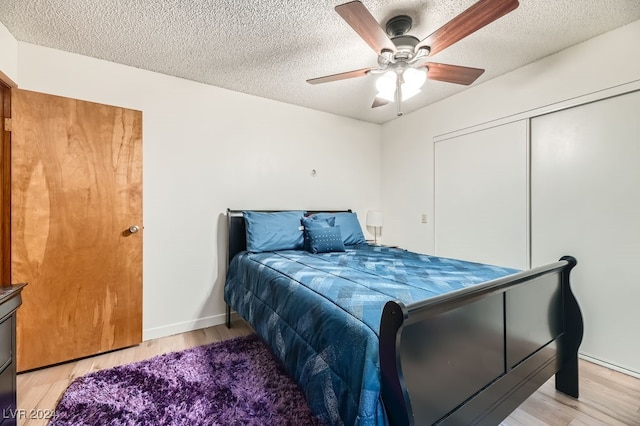 bedroom with ceiling fan, a closet, a textured ceiling, and light hardwood / wood-style flooring