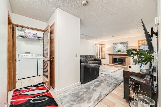 interior space featuring track lighting, washer and dryer, a textured ceiling, and light wood-type flooring