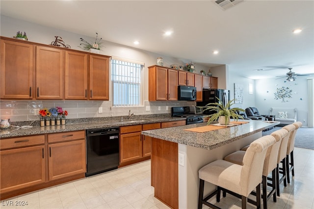 kitchen featuring black appliances, a kitchen island, a kitchen bar, and backsplash