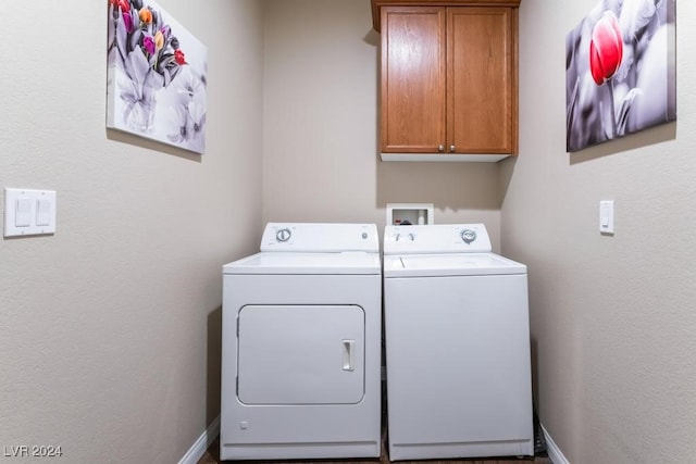 clothes washing area featuring washing machine and dryer and cabinets