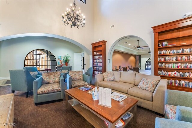 carpeted living room with ceiling fan with notable chandelier and a towering ceiling