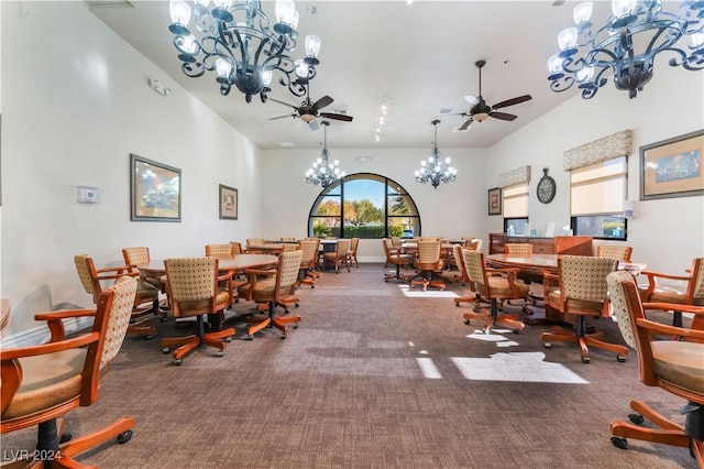 carpeted dining area with ceiling fan with notable chandelier and a towering ceiling