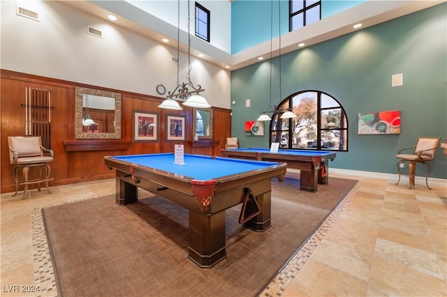 playroom with a towering ceiling, wood walls, and billiards