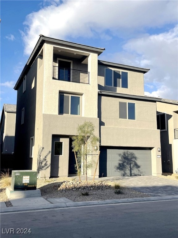 view of front of property with driveway, a balcony, an attached garage, and stucco siding