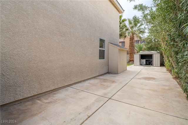 view of side of property featuring a patio and a storage unit