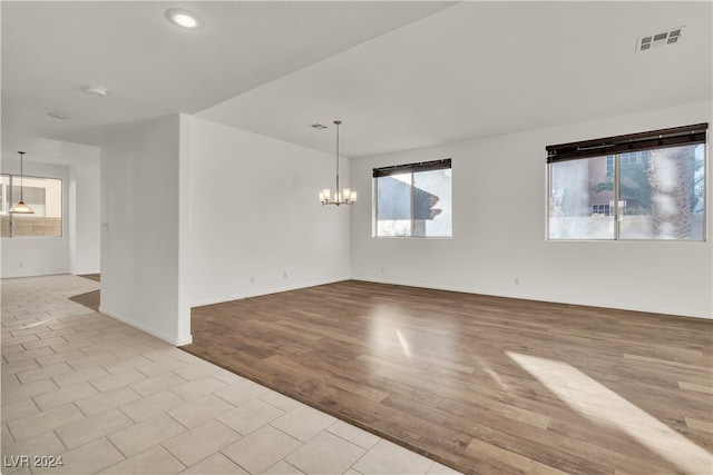 empty room featuring a chandelier and light wood-type flooring