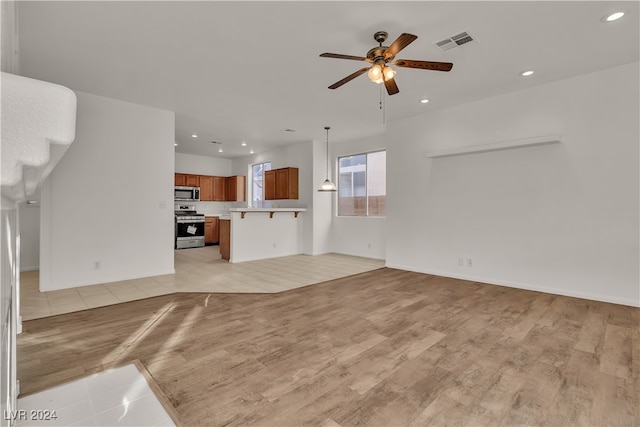 unfurnished living room featuring ceiling fan and light hardwood / wood-style flooring